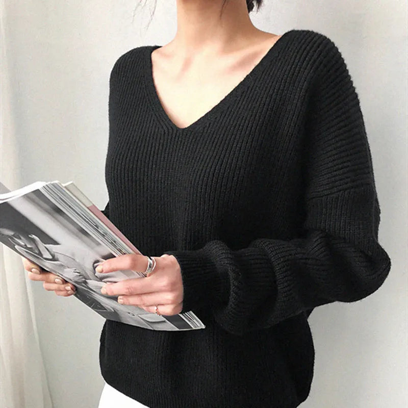 Person wearing a black sweater holding a magazine against a white background #Color_Black