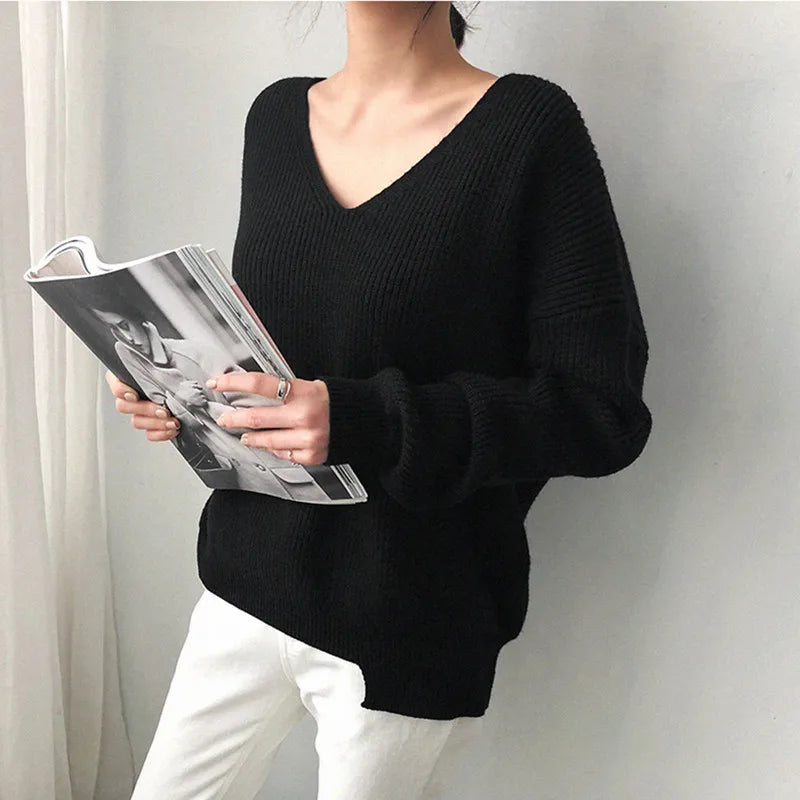 Person wearing a black sweater holding a magazine against a plain background #Color_Black