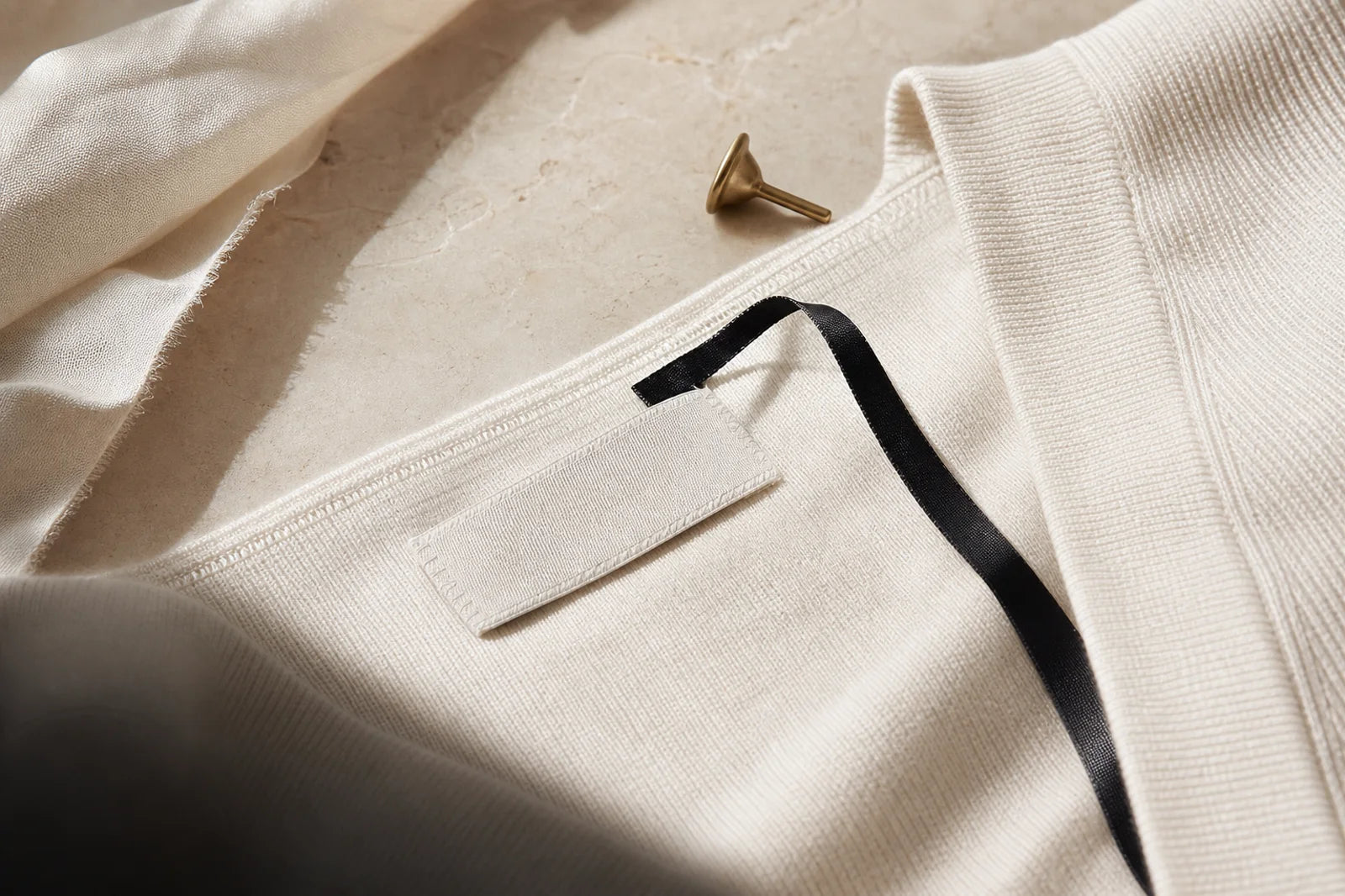 Close-up of premium knitwear finishing on a stone atelier table