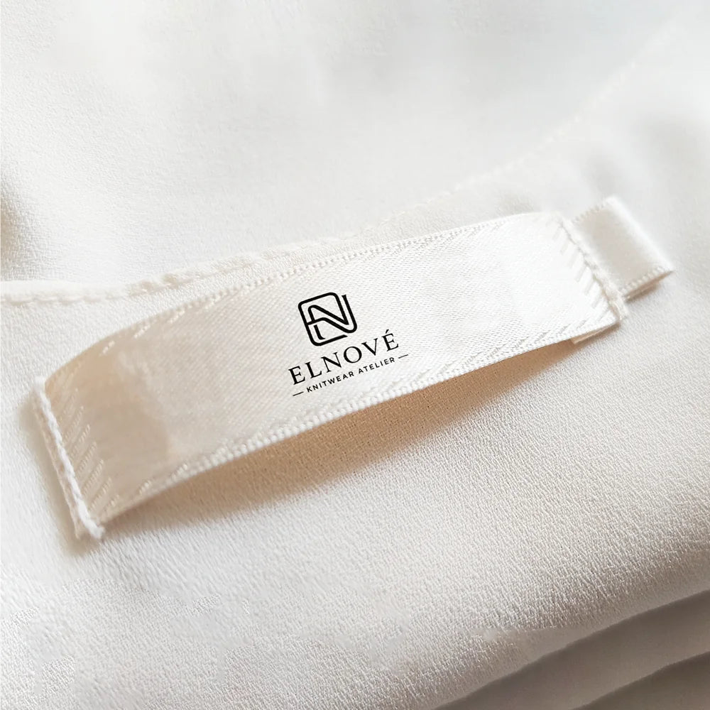 ELNOVE woven garment label on cream fabric